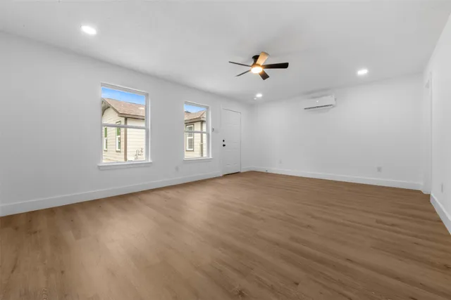 a view of an empty room with a window and wooden floor