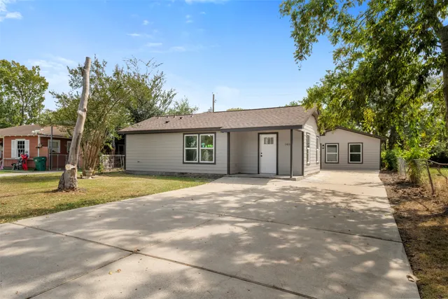 a front view of a house with a garden and tree