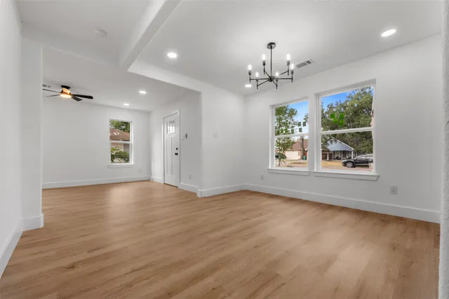 a view of an empty room with window and wooden floor