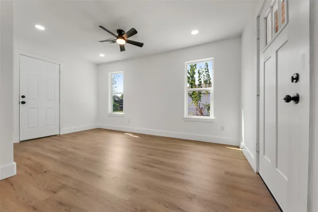 a view of an empty room with wooden floor and a window