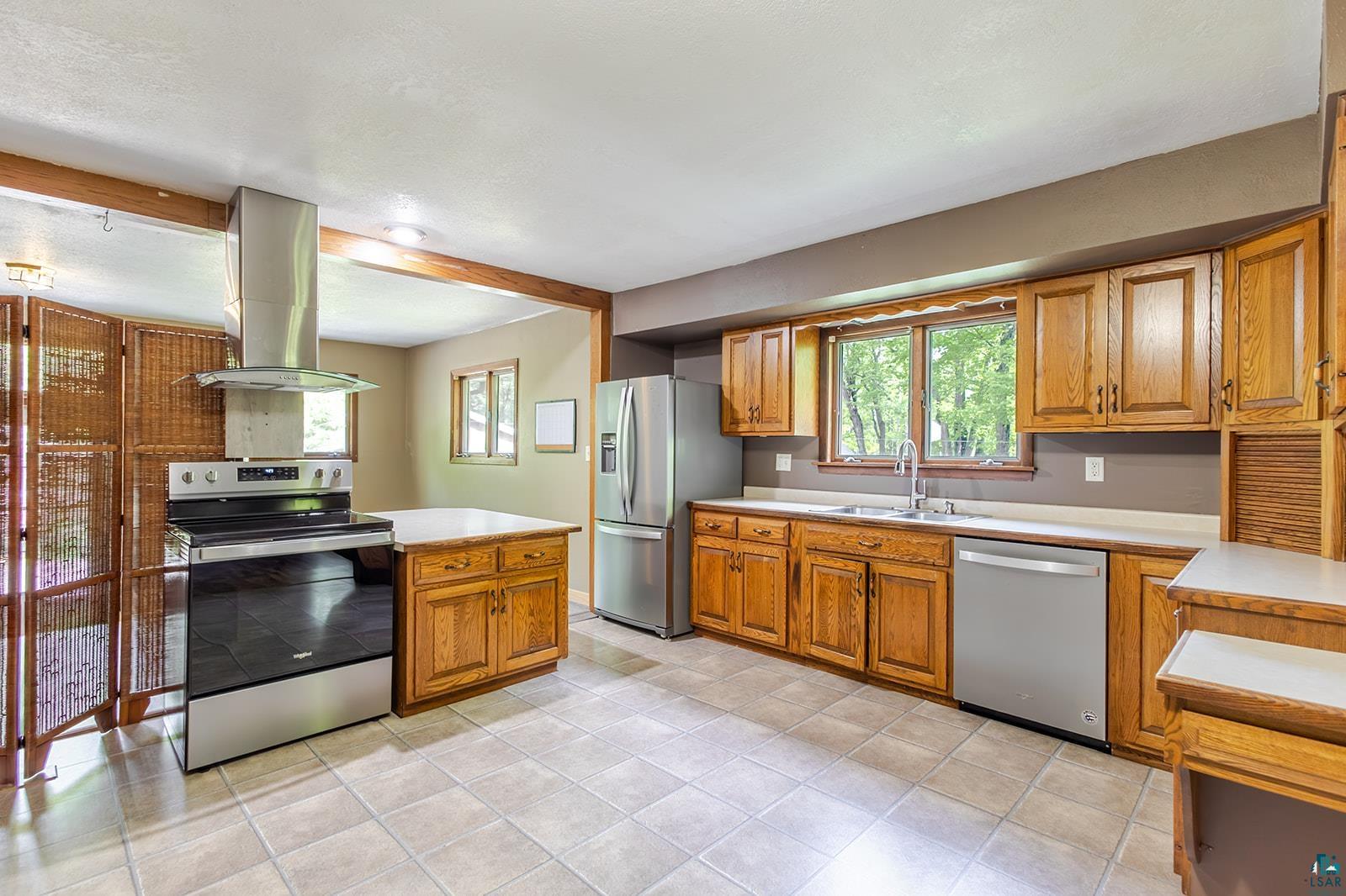 7045 Morris Thomas Road Cloquet, MN 55720 - Photo 8 of 28 Kitchen featuring wood cabinetry, stainless steel appliances, a center island with countertop, and tile flooring