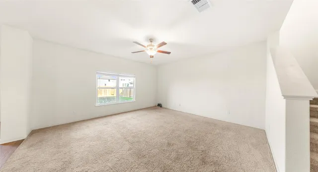 an empty room with windows and a ceiling fan