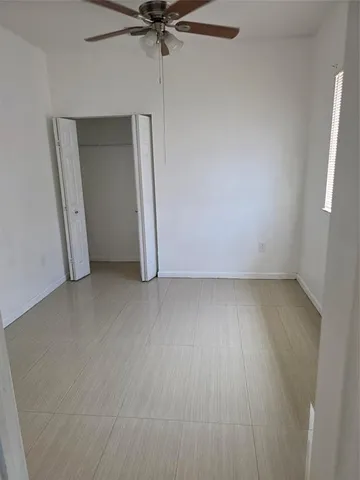 an empty room with a fan and a window