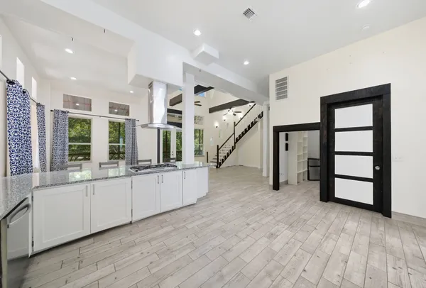 a large white kitchen with granite countertop a large white kitchen island a sink and dishwasher a oven with wooden floor