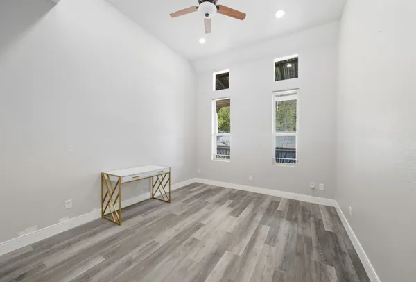 an empty room with windows and ceiling fan