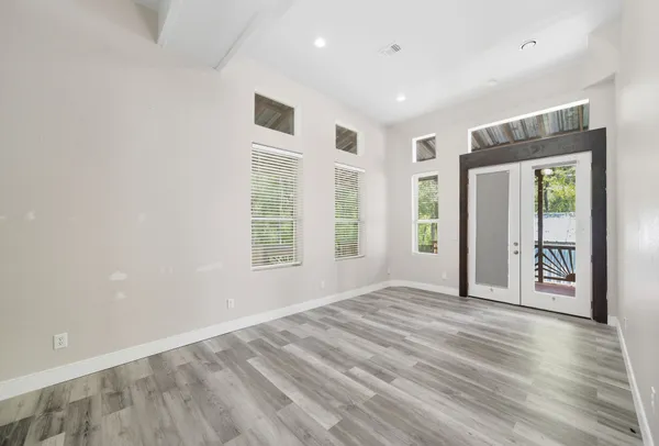 a view of an empty room with a window and wooden floor