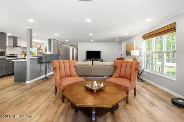 a living room with stainless steel appliances furniture a rug and a kitchen view