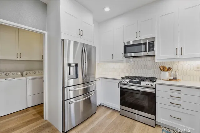 a kitchen with cabinets stainless steel appliances and wooden floor