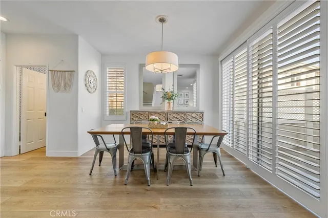 a dining room with wooden floor a chandelier a wooden table and chairs