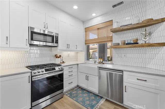 a kitchen with stainless steel appliances granite countertop a stove a sink and a microwave