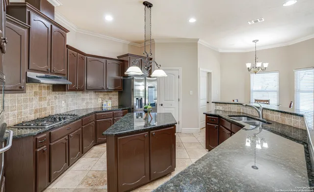 a kitchen with stainless steel appliances granite countertop a sink a stove and a wooden floors