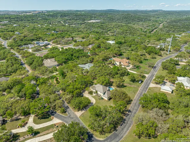an aerial view of residential houses with outdoor space and trees