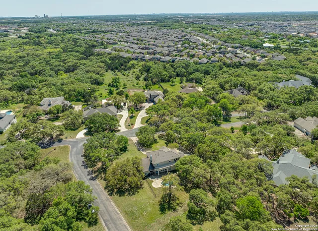an aerial view of residential houses with outdoor space and trees