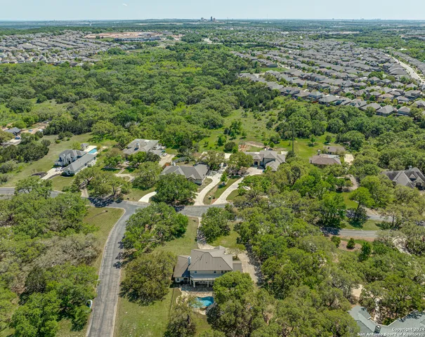 an aerial view of residential houses with outdoor space and trees