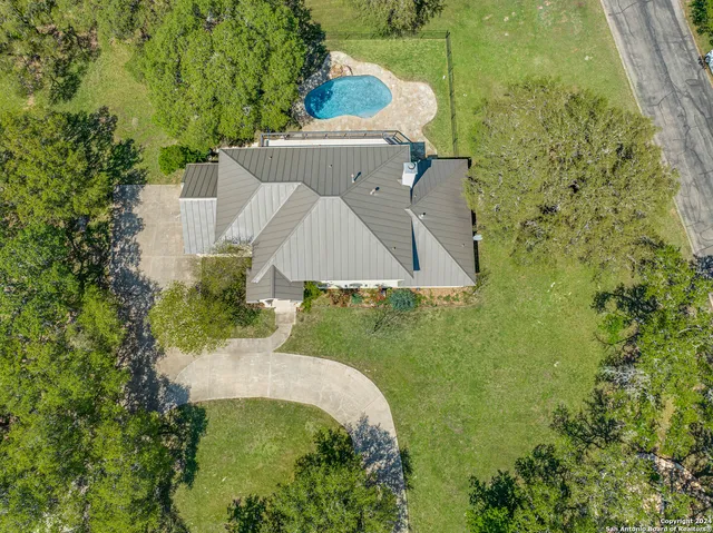 an aerial view of a house with a yard and trees all around