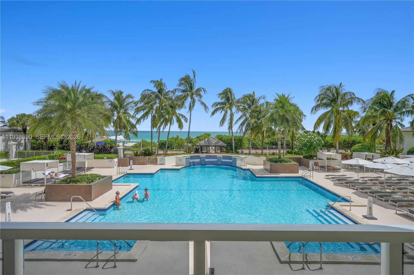 4779 Collins Avenue, Unit 3104 Miami Beach, FL 33140 - Photo 59 of 61 a view of a swimming pool with a lawn chairs and palm tree