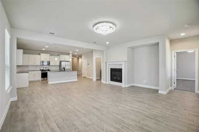 a view of an empty room with kitchen and fireplace