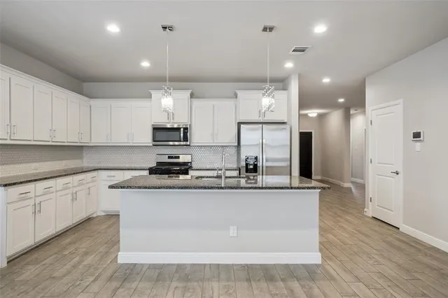 a kitchen with granite countertop white cabinets and white appliances with wooden floor