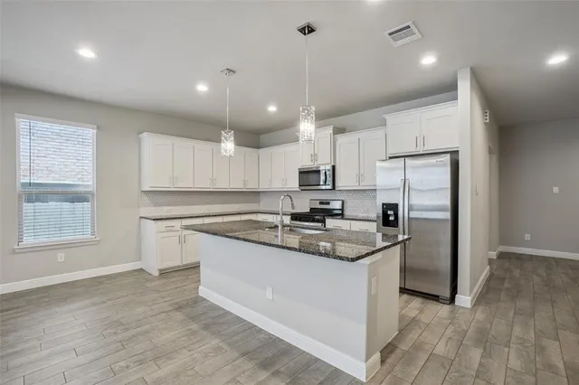 a large kitchen with cabinets wooden floor stainless steel appliances and cabinets