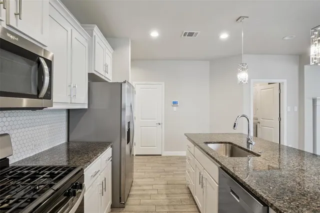 a kitchen with stainless steel appliances granite countertop a sink and a stove