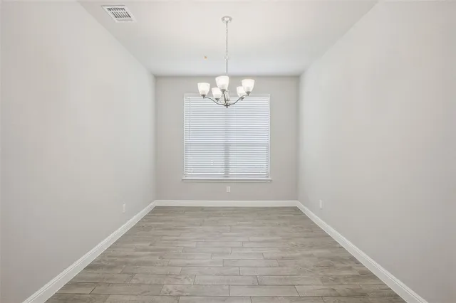 en empty room with wooden floor chandelier and window