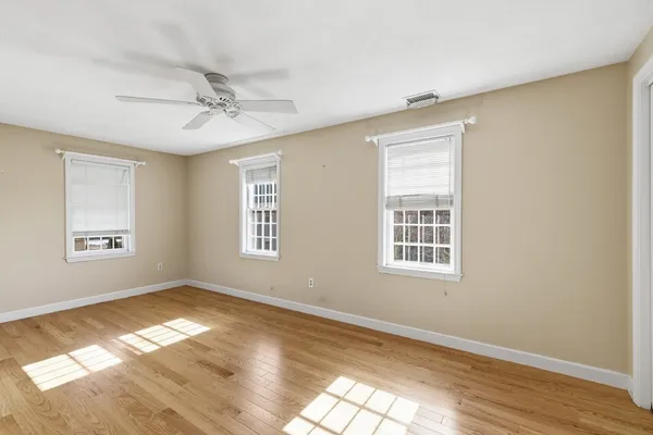 a view of empty room with wooden floor and fan