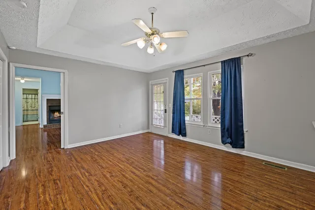 a view of an empty room with wooden floor and a window