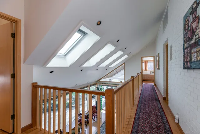 a bedroom with a bed and large window with wooden floor