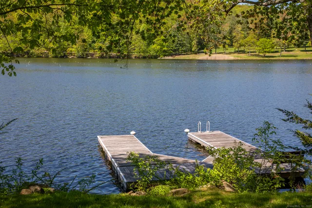 a view of a lake with lawn chairs and wooden fence