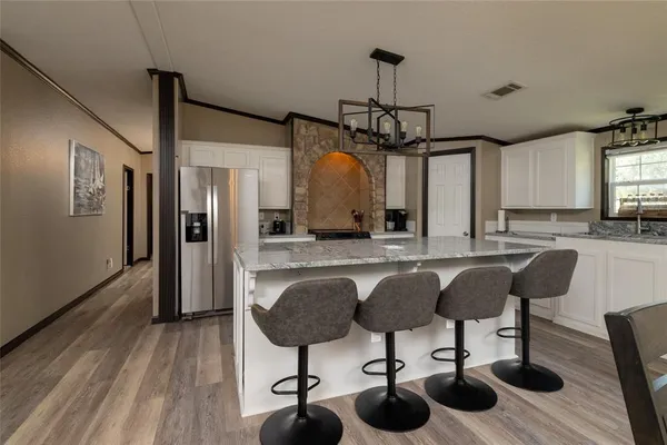 a kitchen with stainless steel appliances granite countertop a sink a refrigerator and wooden floor