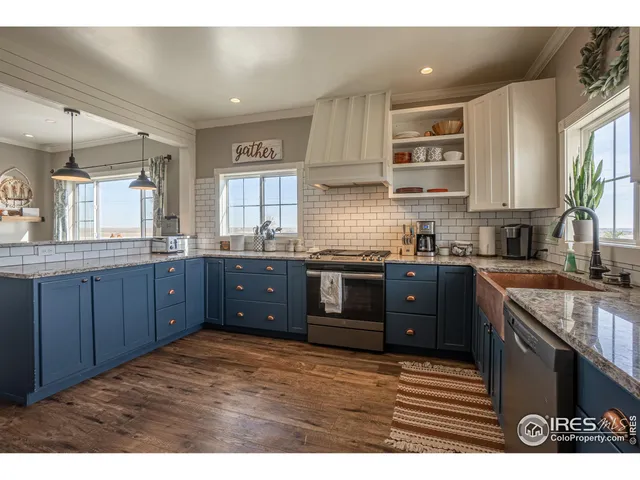 a kitchen with stainless steel appliances granite countertop a sink a stove a refrigerator cabinets and a window