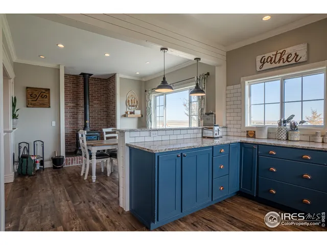a kitchen with kitchen island granite countertop a stove a sink dishwasher and cabinets with wooden floor