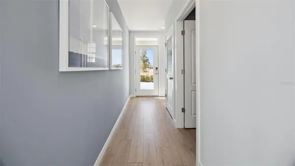 a view of a hallway with wooden floor and a bathroom