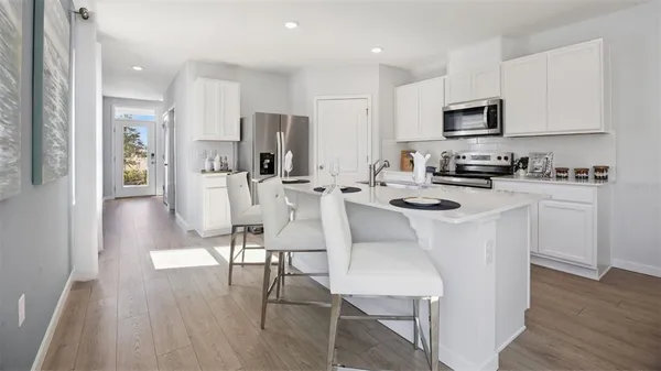 a white kitchen with stainless steel appliances a white table and chairs in it