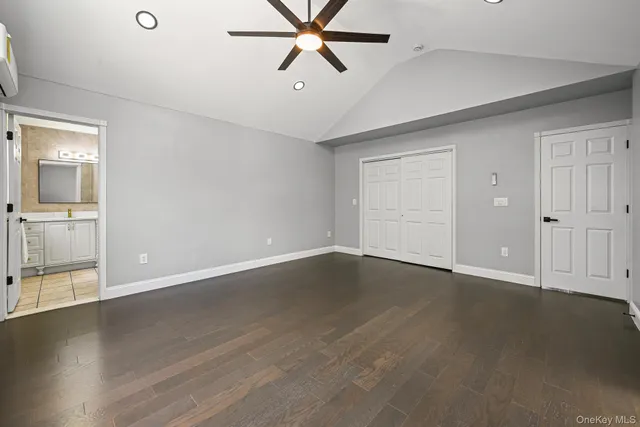 an empty room with wooden floor cabinet and windows