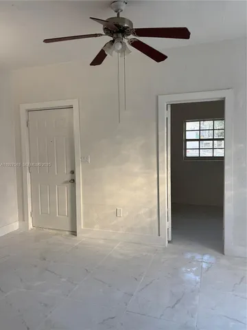 a view of an empty room with a fan and a window