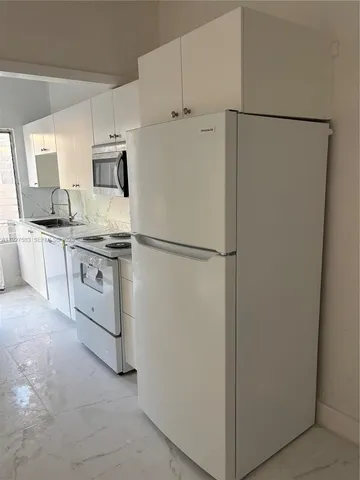 a white refrigerator freezer and a stove sitting inside of a kitchen