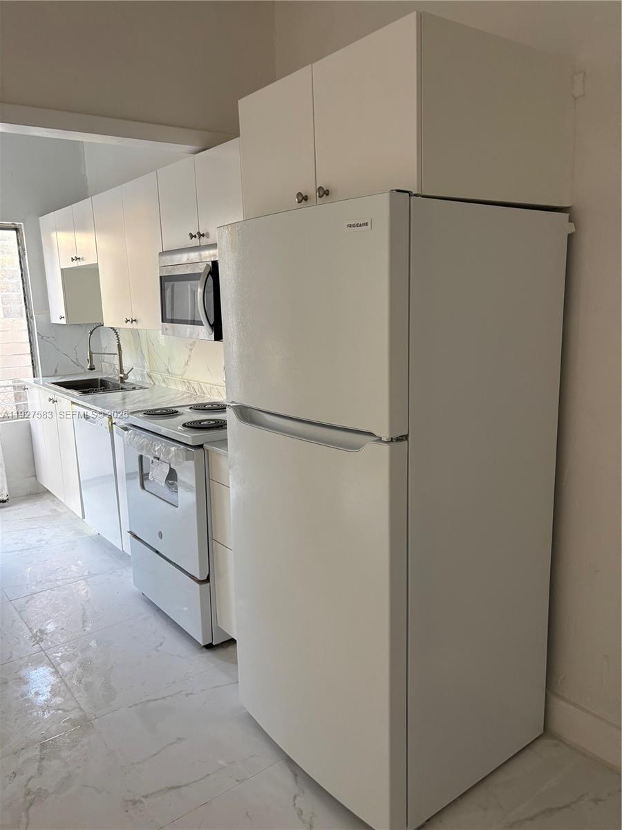 568 Southwest 3rd Street, Unit LEFT 566 Miami, FL 33130 - Photo 7 of 17 a white refrigerator freezer and a stove sitting inside of a kitchen