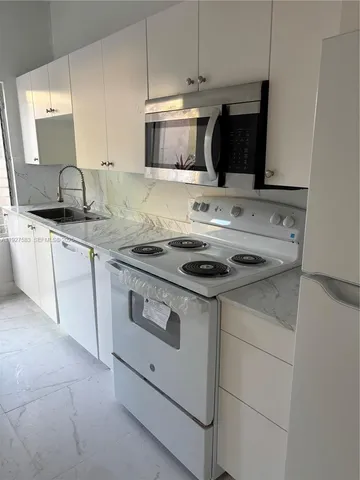 a kitchen with granite countertop a sink stove and microwave