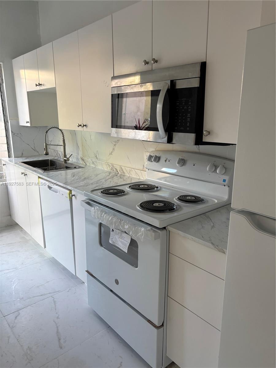 568 Southwest 3rd Street, Unit LEFT 566 Miami, FL 33130 - Photo 8 of 17 a kitchen with granite countertop a sink stove and microwave