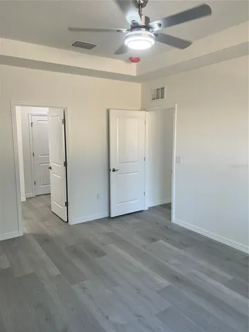 en empty room with wooden floor and ceiling fan