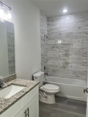 a bathroom with a granite countertop toilet a sink and a mirror