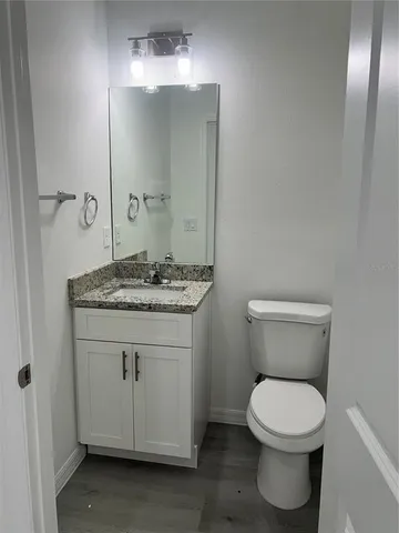 a bathroom with a granite countertop toilet a sink and mirror