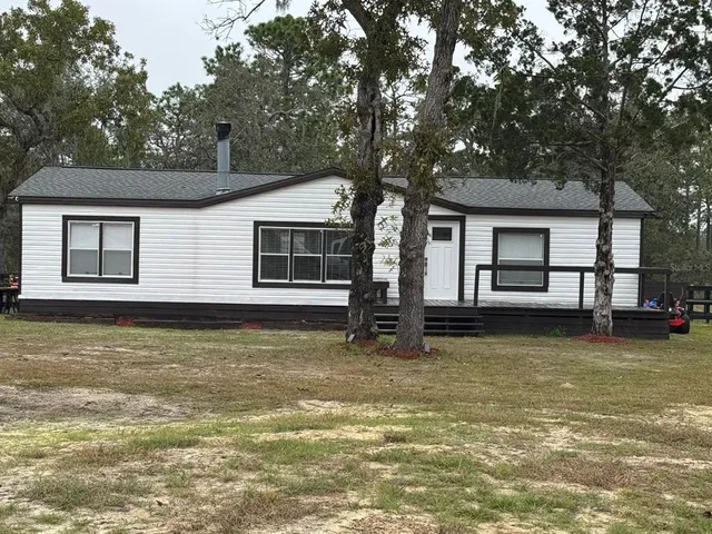 a view of a house with a large tree and a yard