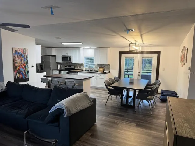 a living room with stainless steel appliances furniture a fireplace a flat screen tv and a window