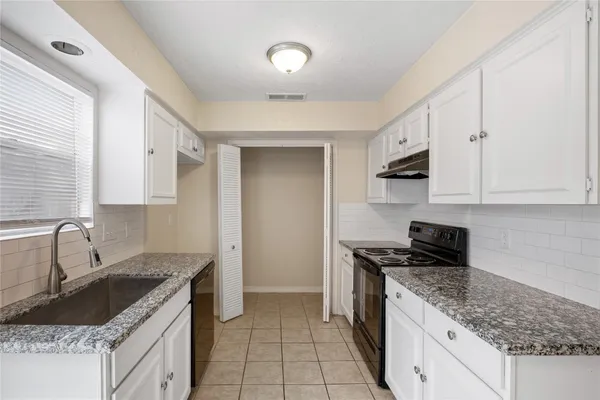 a kitchen with granite countertop a sink stove and cabinets