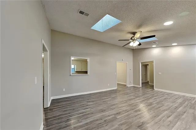 a view of an empty room with wooden floor and a ceiling fan