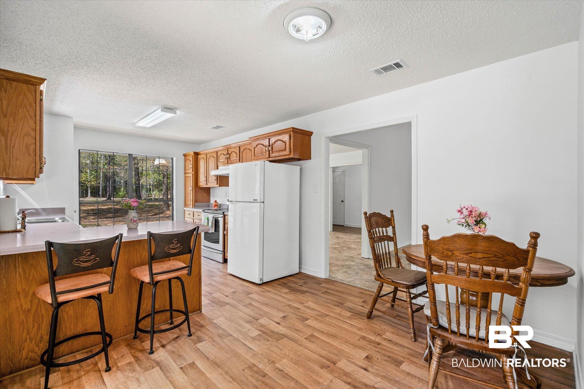 9770 Lakeview Road Bay Minette, AL 36507 - Photo 11 of 44 Kitchen with freestanding refrigerator, a breakfast bar area, a peninsula, light countertops, and a textured ceiling