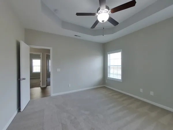 an empty room with chandelier fan and windows