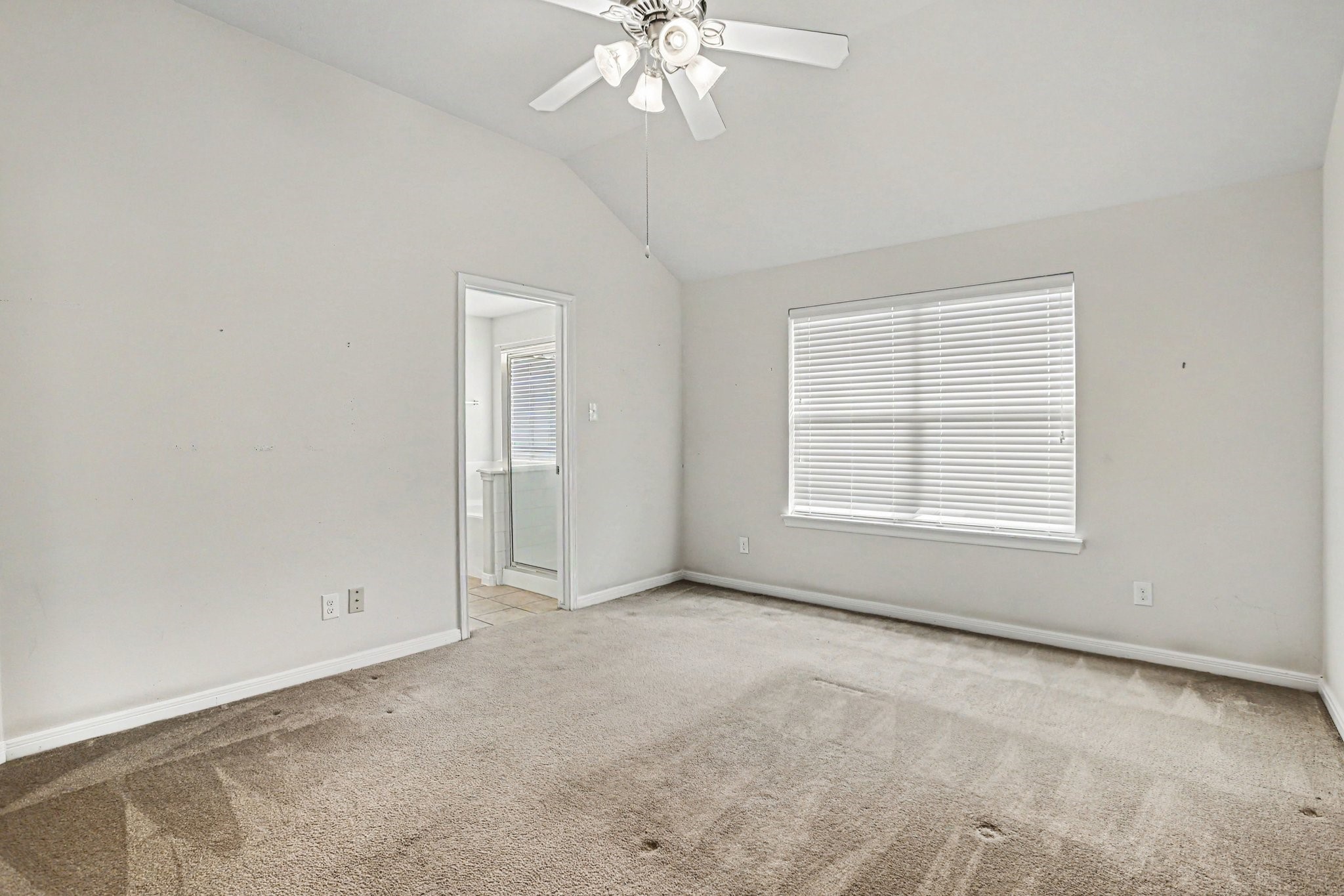 25222 Ginger Ranch Drive Katy, TX 77494 - Photo 20 of 33 The primary bedroom with neutral walls, carpet flooring, a ceiling fan, and a large window with blinds allowing natural light.